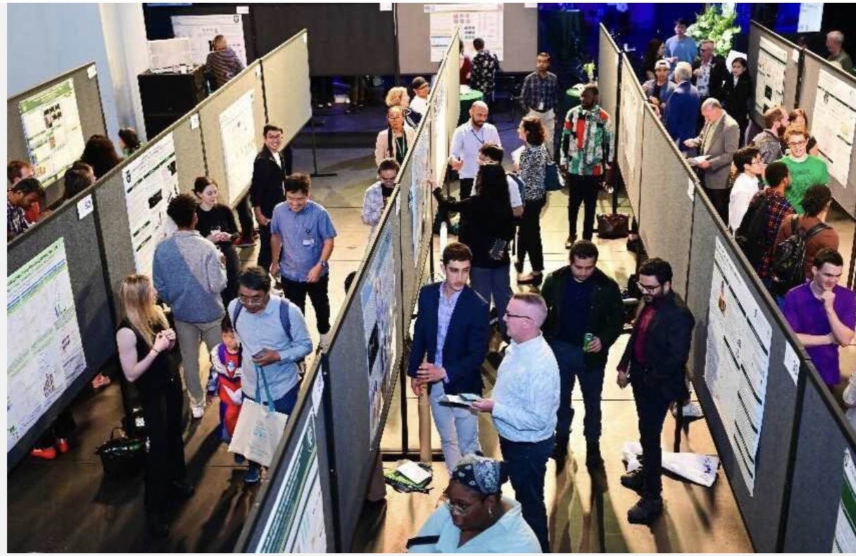 People engaging at a busy indoor conference poster session.